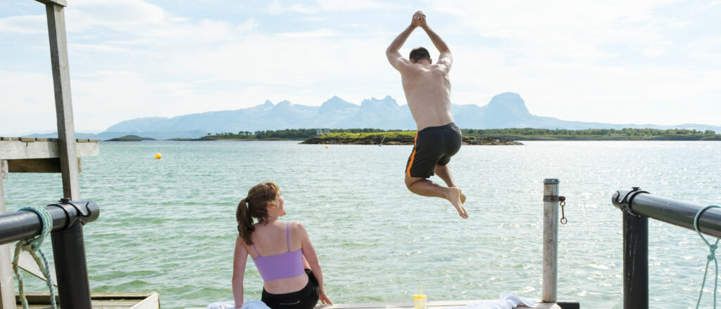 En mann og kvinne på badetur på Herøy foran De Syv Søstre