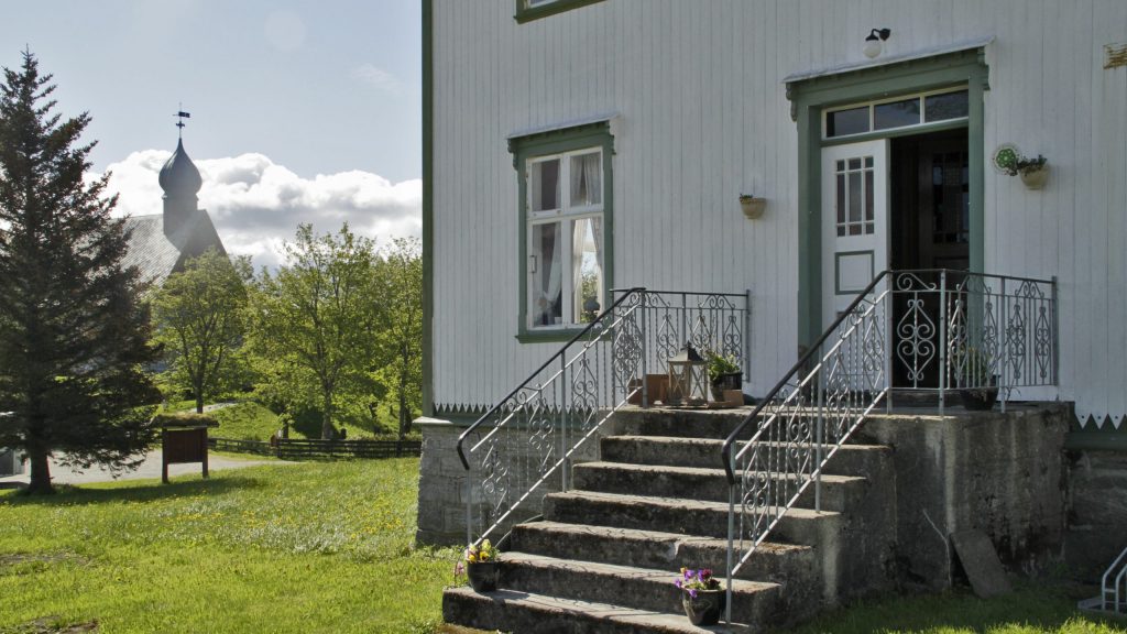 Inngangsparti med trapp inn Dønnes Gård. I bakgrunnen til venstre mellom trær står Dønnes kirke