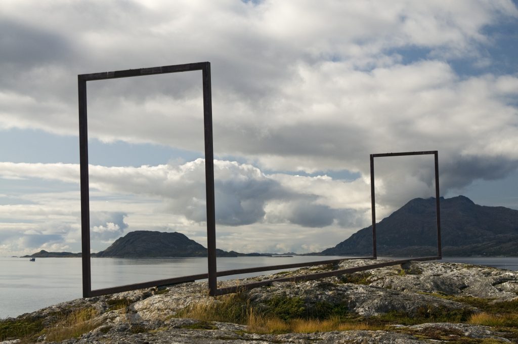 Metallskulptur oppå et berg. Met utsikt over havet.