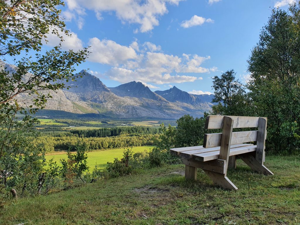 Utsikt mot fjellkjeden De Syv Søstre sett fra en sittebenk i naturen en solskinnsdag