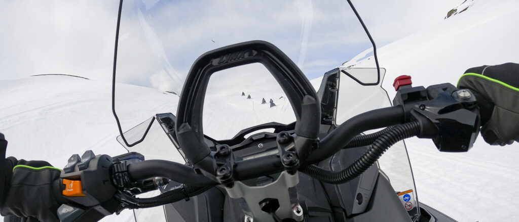 Snøskutertur i skuterløype sett fra førerens perspektiv fra en snøskuter med flere snøskutere i løypa foran
