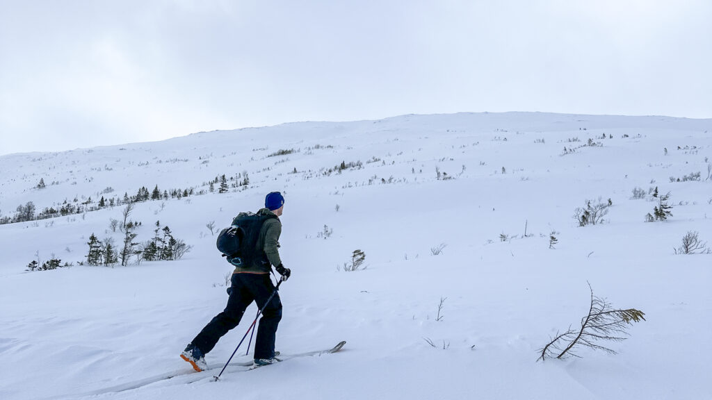 Person med ryggsekk og ski på vei opp mot fjelltoppen Steinlikammen