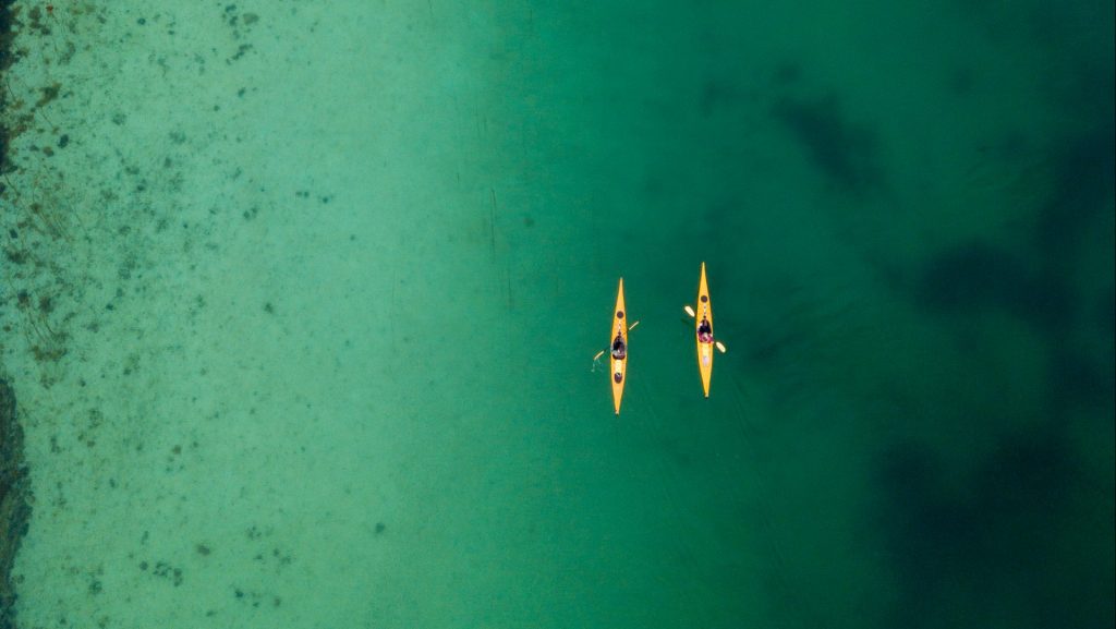 To kajakker i vannet ved Herøy sett fra lufta