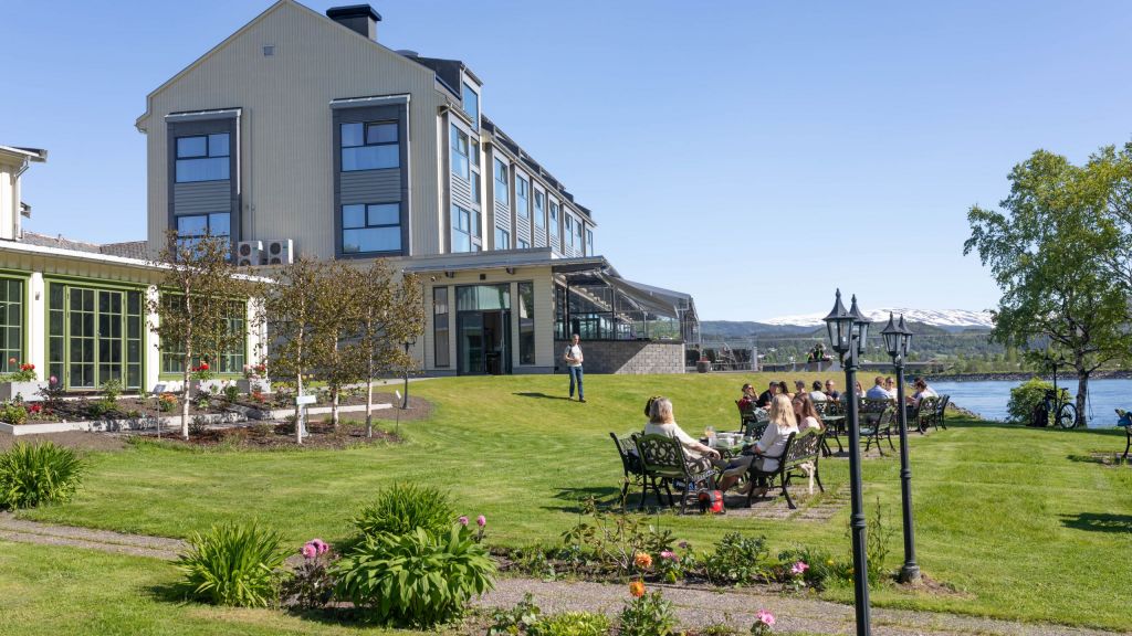 Nydelig hotellhage foran Fru haugans Hotel i Mosjøen. Par som sitter på benk i hagen.