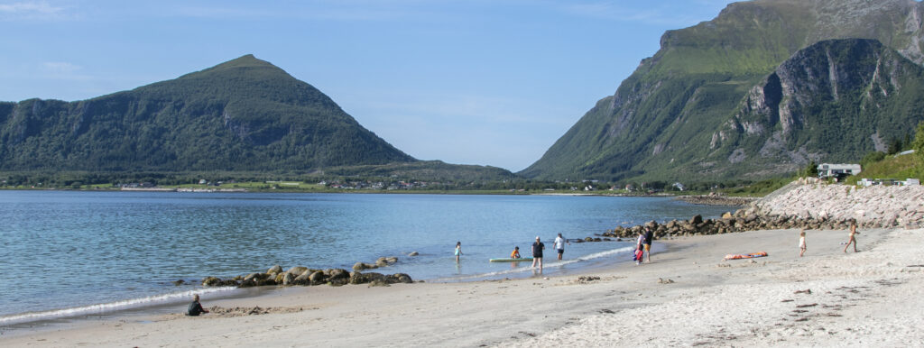 Folk bader og koser seg på stranda ved Stia badeplass en fin sommerdag