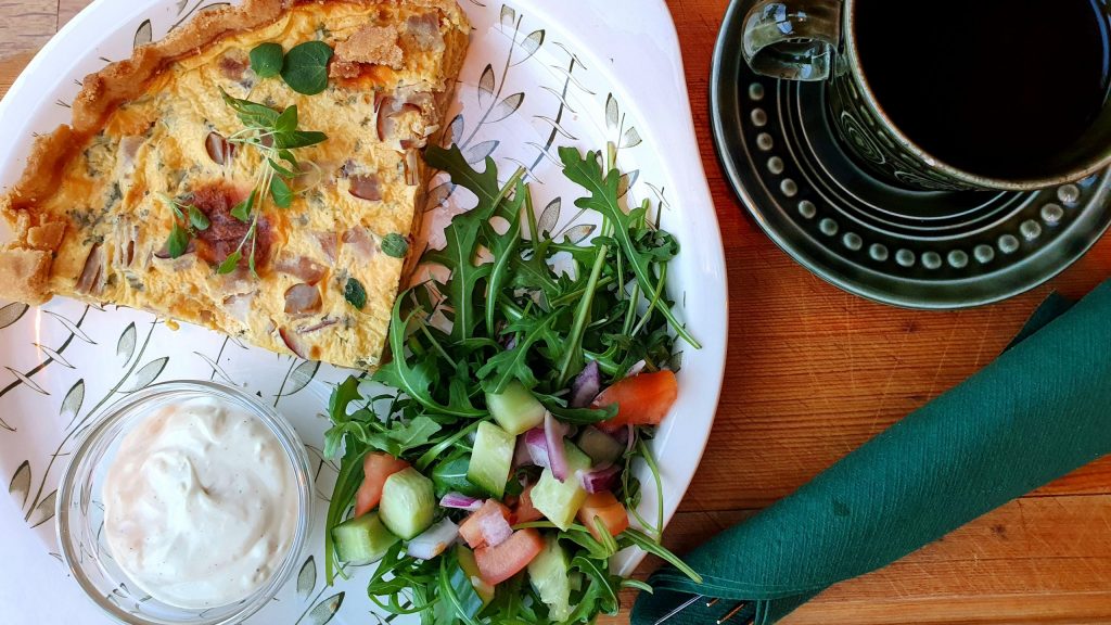 Askeladden Ressurssenter-kaffen og kruse-lunch-foto Kamilla Fagerland Tallerken med pai, salat og dressing i skål. Kaffekopp og bestikk.