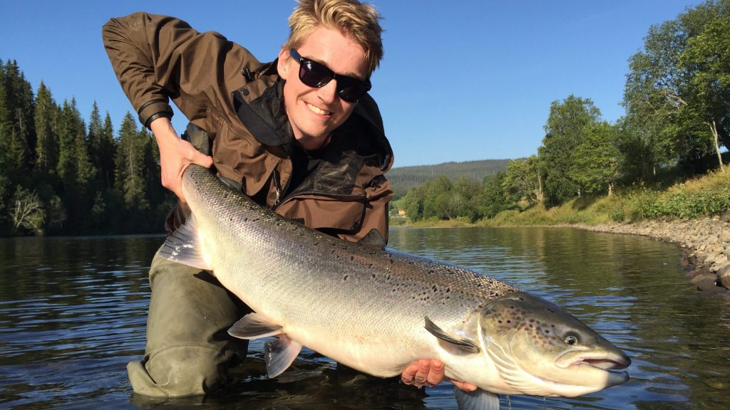 Fisker i elva med en stor laks i hendene