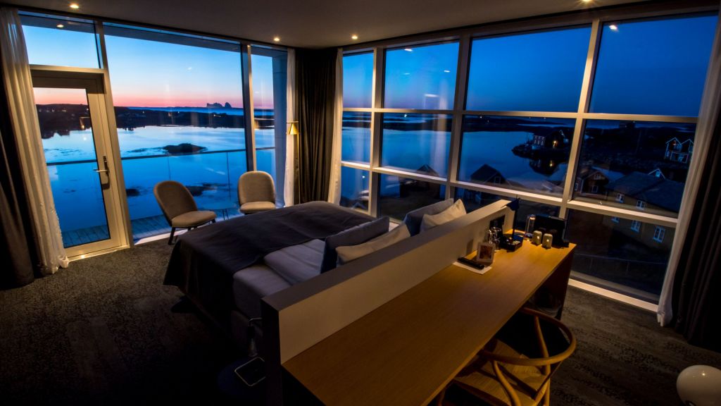 Hotellrom med hjørnevinduer og nydelig utsikt mot havet og Træna i kveldslys