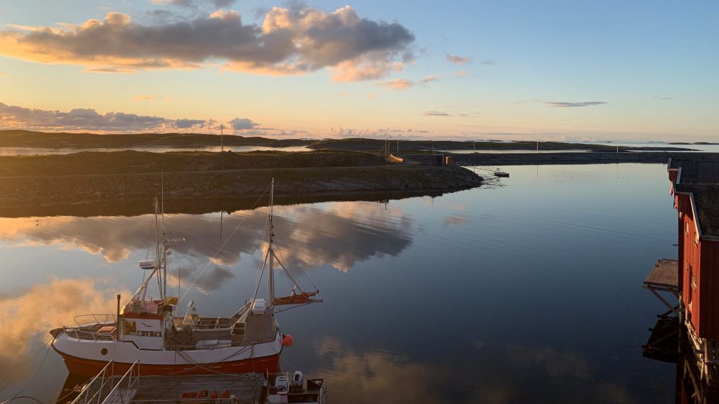 Sjark som ligger ved flytekai i sundet i kveldssol