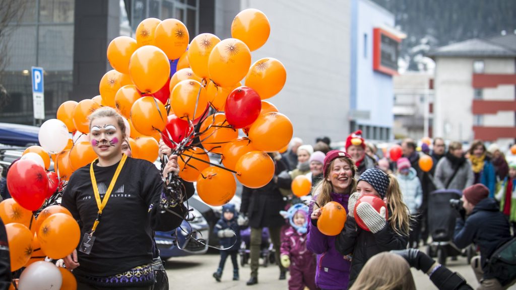 Mennesker ute i gaten med ansiktsmaling og ballonger