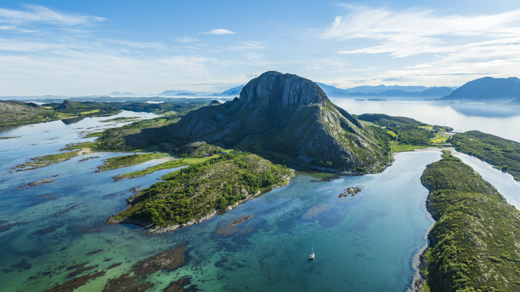 Sagnfjellet Torghatten sett fra luften en tidlig sommermorgen med en seilbåt i forgrunnen