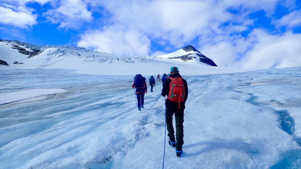 Gruppe som går i taulag med stegjern på isbre