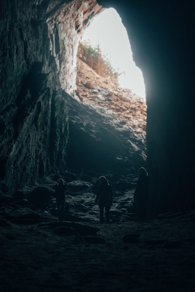 Tonnesgrotta sett innenfra mot utgangen med tre personer i front.