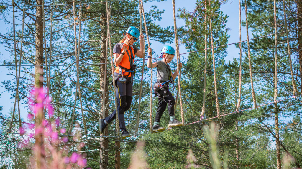 Folk som klatrer i høyt og lavt klatrepark en sommerdag