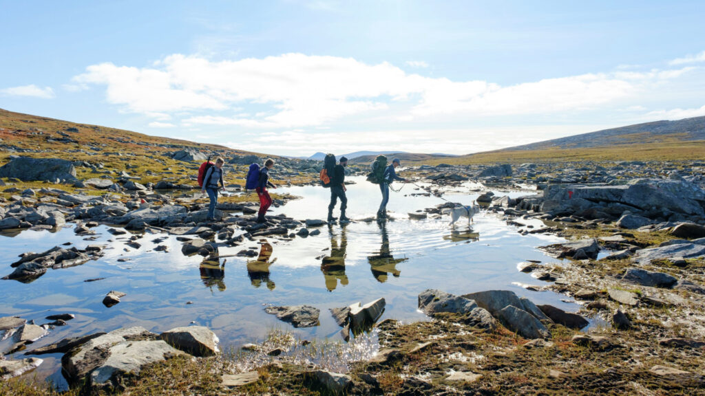 Turgruppe krysser en bred bekk på Saltfjellet