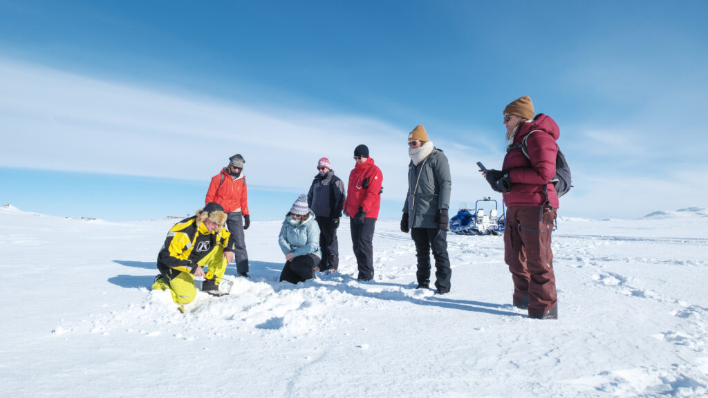 Gruppe på fjelltur på vinteren får opplæring i isfiske